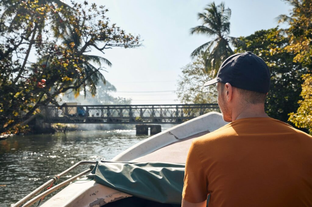 Man traveling on boat against bridge in beautiful tropical landscape. Madu River in Sri Lanka.