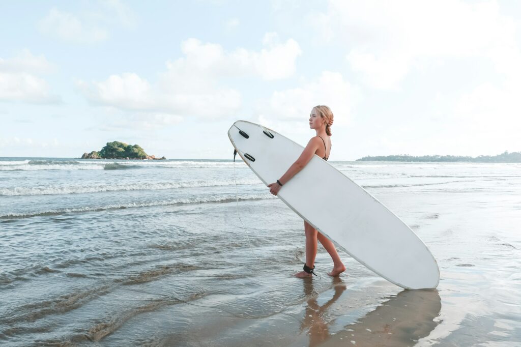 Surfing, Girl surfer with a longboard on the beach of Weligama, Indian Ocean Active water sports, tr